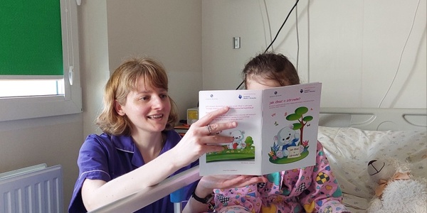 Nauczycielka czyta dziecku broszurę edukacyjną Jak dbać o zdrowie