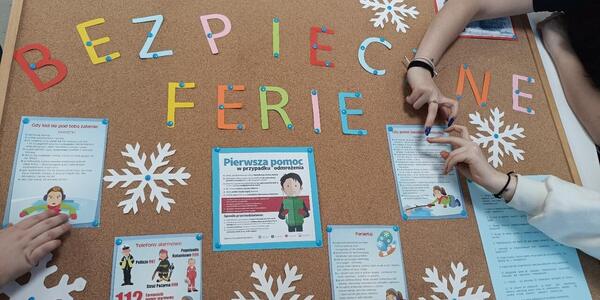 uczniowie wieszają informacje przypominające o bezpieczeństwie podczas ferii zimowych