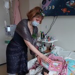 Dziecko ogląda książkę, którą trzyma Pani rybka akwariowa