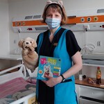Nauczycielka w kociej opasce, trzyma książkę o kotku i pluszowego kociaka