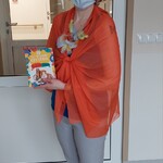 Nauczycielka w przebraniu za papugę ozdobiona w kolorowe piórka trzyma książkę o zwierzętach domowych