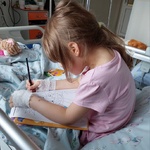 Dziewczynka koloruje kredkami ilustrację Pani Wiosny
