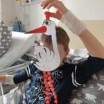 Chłopiec trzyma papierowego bociana