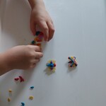Dziecko układa na stoliku wykonane owady z makaronu i plasteliny