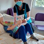 Dziecko wraz z nauczycielką rozwiązuje zagadki w Wielkiej Księdze Wakacji