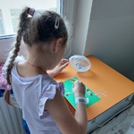 Dziewczynka bawi się kreatywnie tworząc obrazek z materiałów sypkich