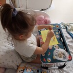 Dziewczynka rozsypuje na kartce płatki owsiane i mąkę, ustawia makaroniki