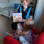 Nauczycielka zachęca dziecko do rozmowy Jak się zachować na wakacjach w oparciu o książkę z ilustracjami i opowiadaniami