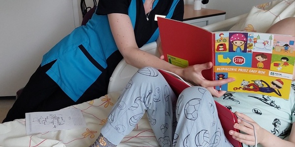 Nauczycielka zachęca dziecko do rozmowy o bezpieczeństwie w trakcie wakacyjnych zabaw w oparciu o broszurę edukacyjną
