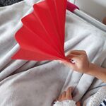 Dziecko trzyma w dłoni samodzielnie wykonany z papieru wachlarz
