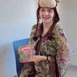 Nauczycielka w przebraniu za małpkę trzyma książkę o małpce wśród przyjaciół