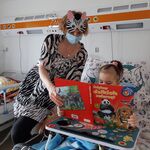 Nauczycielka w stroju zebry czyta dziecku o dzikich egzotycznych zwierzętach i zachęca do naśladowania ich odgłosów