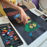 Słoneczna galeria – Urtica Dzieciom - chłopiec w sali separatkowej tworzy pastelami kolorową sowę