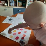 dziewczynka stempluje pomalowaną połówką jabłka