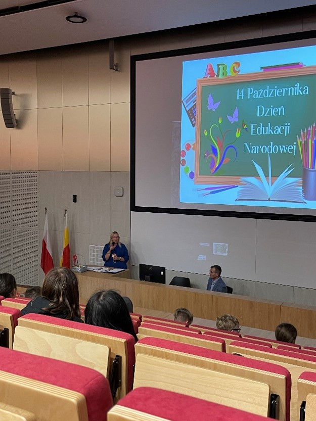aula z dużym ekranem projekcyjnym z grafiką z okazji dnia edukacji narodowej
