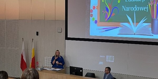 aula z dużym ekranem projekcyjnym z grafiką z okazji dnia edukacji narodowej