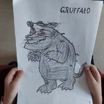 Dziecko trzyma ilustrację stwora z opowieści, którego pokolorowało