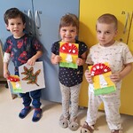Troje dzieci prezentuje wykonane przez siebie prace- muchomorki.