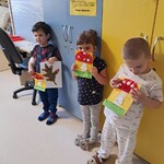 Troje dzieci prezentuje wykonane przez siebie prace- muchomorki.