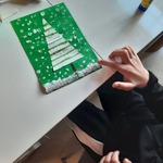 chłopiec tworzy pocztówkę z choinką