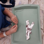 Dziecko wykonuje ozdobę sopelkowe-lodową ze sznurka i folii aluminiowej