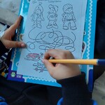 Dziecko sprawdza wodząc po lini do kogo sprzęt zimowy należy i koloruje sanki, narty