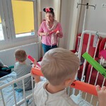Dzieci uczą się grać na bum bum rurkach według pokazu nauczycielki