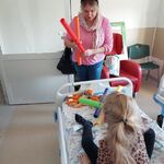 Dziewczynka bierze udział w zabawie z bum bum rurkami prowadzonej przez nauczycielkę