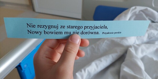 W ręku dziecka pasek z cytatem Nie rezygnuj ze starego przyjaciela. Nowy bowiem mu nie dorówna