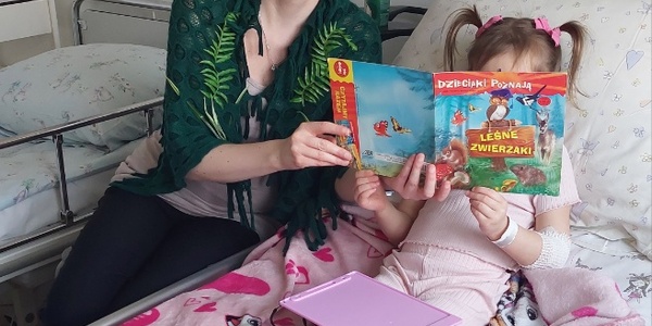 Nauczycielka czyta dziecku książkę o leśnych zwierzętach w przebraniu za jeża
