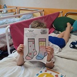 Chłopiec na łóżku pokazuje swoją pracę