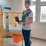 Nauczycielka w kreatywnym przebraniu za Panią Ślimakową trzyma kwiatka z zagadkami zapisanymi na liściach