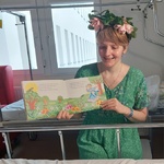 Nauczycielka w przebraniu za Panią Wiosnę czyta i pokazuje ilustracje w książce o wiośnie