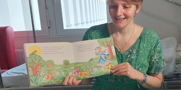 Nauczycielka w przebraniu za Panią Wiosnę czyta i pokazuje ilustracje w książce o wiośnie