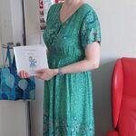 Nauczycielka w przebraniu za Panią Wiosnę, w Zielonej sukience i wianuszku z kwiatów i liści prezentuje książkę o wiośnie