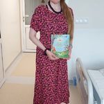 Nauczycielka jako Pani Lato w kapeluszu i kwiatowej, różowej sukience trzyma książkę Lato