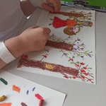 Dziecko rysuje kredkami pastelowymi Panią Jesień w sadzie