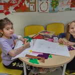 Dwie dziewczynki przy stoliku w świetlicy szpitalnej wykonują prace na konkurs.