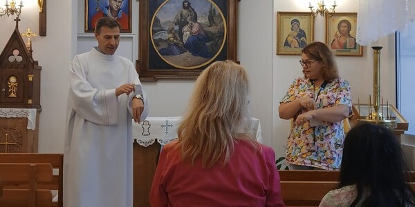 Ksiądz kapelan i pani katechetka ucza piosenki przed nabożeństwem