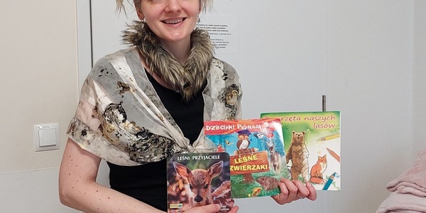 Nauczycielka w przebraniu za zająca prezentuje książki o leśnych zwierzętach