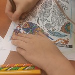 Dziecko maluje mandalę cieniowanymi kredkami