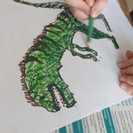 Dziecko koloruje zielonego dinozaura.jpg