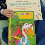 Dziecko pokazuje swój dyplom i kolorowankę
