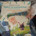 Uczeń pokazuje dyplom i książkę za projekt skarpetki