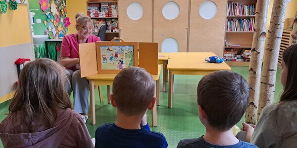 Dzieci oglądają kolejne plansze prezentowane przez nauczycielkę z teatrzyku.
