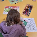 Dziewczynka siedząca przy żółtym stoliku koloruje ilustrację z legendy o Lechu, Czechu i Rusie.