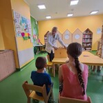 Nauczycielka prezentuje dzieciom zgromadzonym w świetlicy Kliniki Nefrologii skrzynkę butai teatru kamishibai.