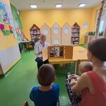 Dzieci oglądają bajkę “Noc w bibliotece” przedstawianą przez nauczycielkę w teatrze kamishibai.