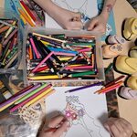 Ręce dzieci kolorujących obrazek Pani Wiosny_ pudełka z kredkami i dziurkacze