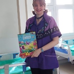 Nauczycielka w przebraniu za motylka prezentuje książkę o owadach